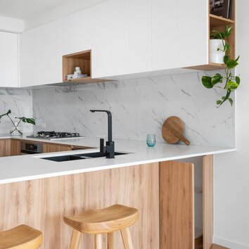 Helle Küche mit schwarzen Elementen, Wandfliesen aus Marmor und hellen Holzfassaden