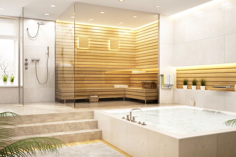 Bagno moderno di colore chiaro con piastrelle in pietra naturale, doccia, vasca idromassaggio e sauna in legno.