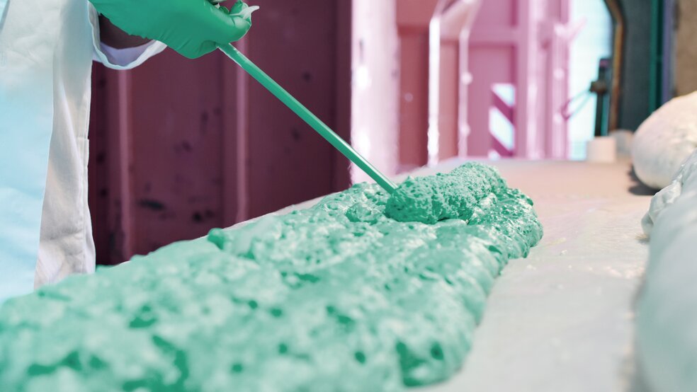 Close-up of green polyurethane foam being applied to a substrate from a cartridge by a Ramsauer employee.